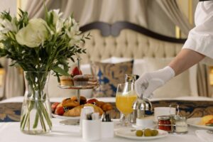 Luxurious hotel room service with pastries, juice, and fresh flowers on a table.